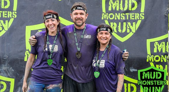 3 people with medals covered in mud