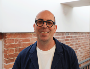 Man headshot smiling at the camera with glasses.