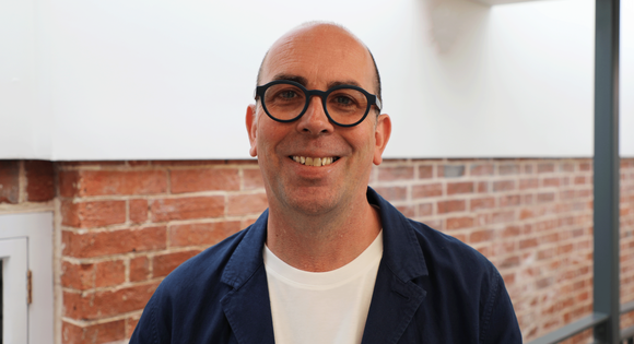 Man headshot smiling at the camera with glasses.