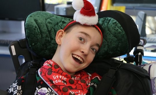 Boy smiling with a Santa hat on.