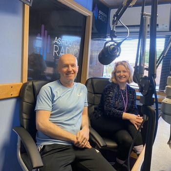 Man and Women smiling while in a radio studio.