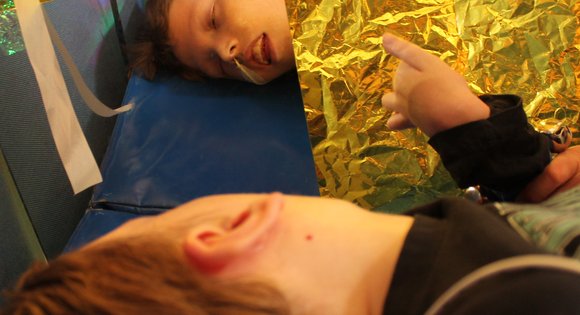 Young person laying down looking in a mirror in sensory art.