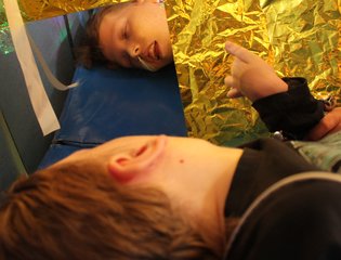 Young person laying down looking in a mirror in sensory art.