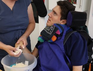Adult man in a wheelchair using a whisk to cook
