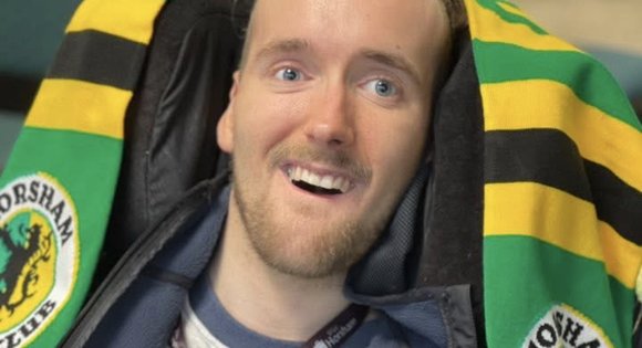 Boy smiling up at camera with a football scarf on.