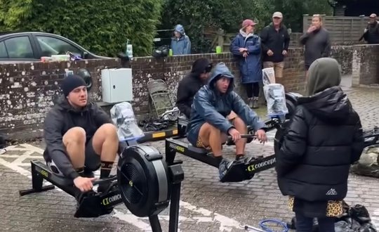 Men rowing outside in a car park.