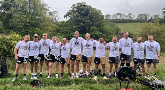 Men standing in a row outside with matching tops on.
