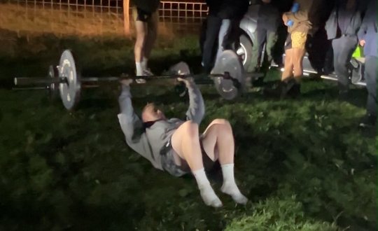 Man lifting weights at night outside.