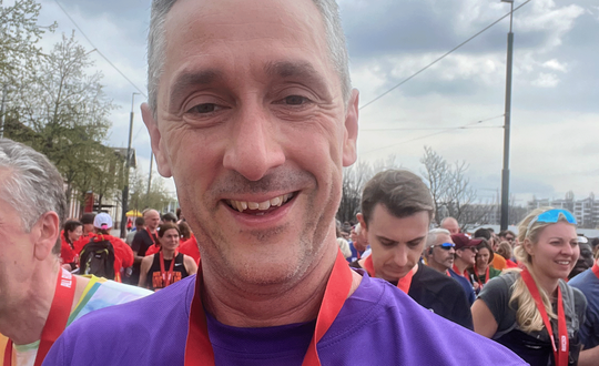 Man smiling with a Prague marathon medal.