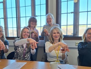 Group of women demonstrating the sign for horse riding.