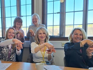 Group of women demonstrating the sign for horse riding.
