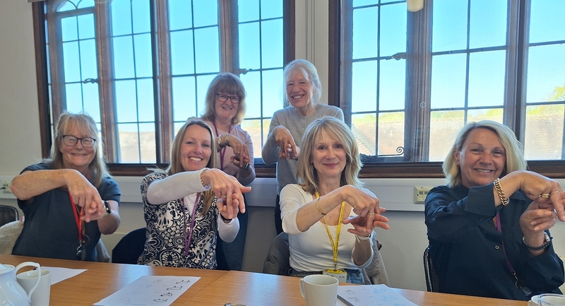 Group of women demonstrating the sign for horse riding.
