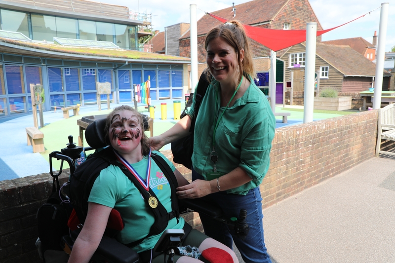 A young girl in a wheelchair who is next to her mum standing