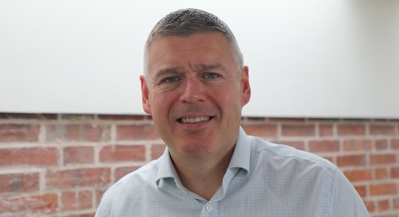 Man headshot smiling at the camera with a shirt on.