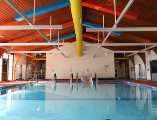 View of a pool indoor with an assistive slide.