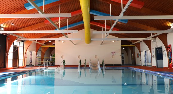 View of a pool indoor with an assistive slide.