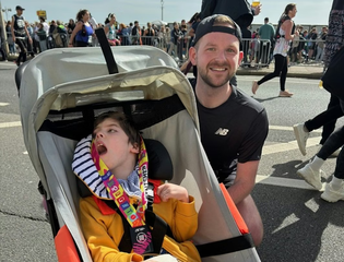 Man and young boy smiling at a running event.