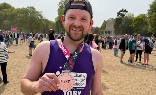 Man smiling with a medal and purple top.