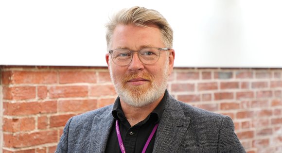 Man smiling with a beard and glasses.
