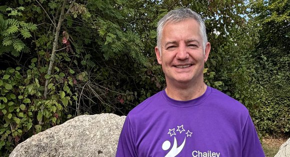 Man with a purple top smiling on a walk.