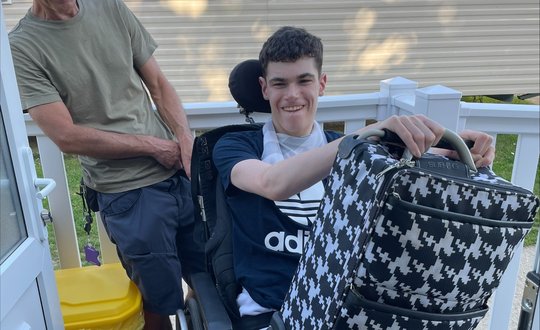 Boy smiling with his suitcase.